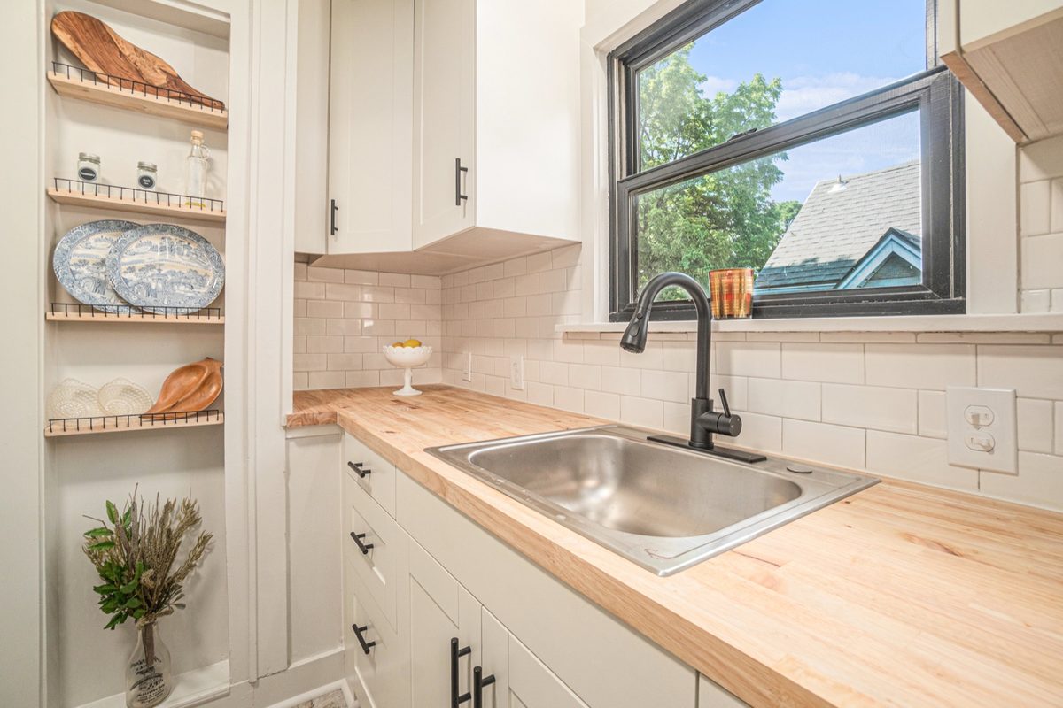 After: bright kitchen with white cabinets, butcher-block counters, and subway tile