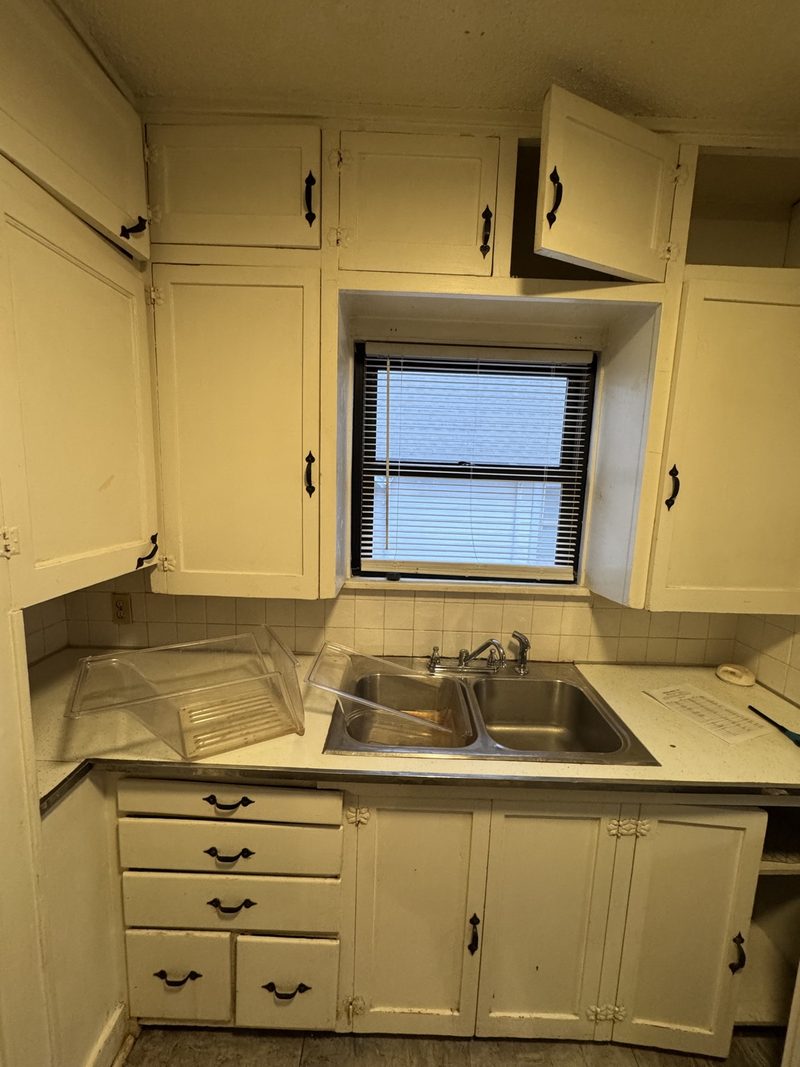 Before: dated kitchen with cream cabinets, ornate hardware, and a tile backsplash