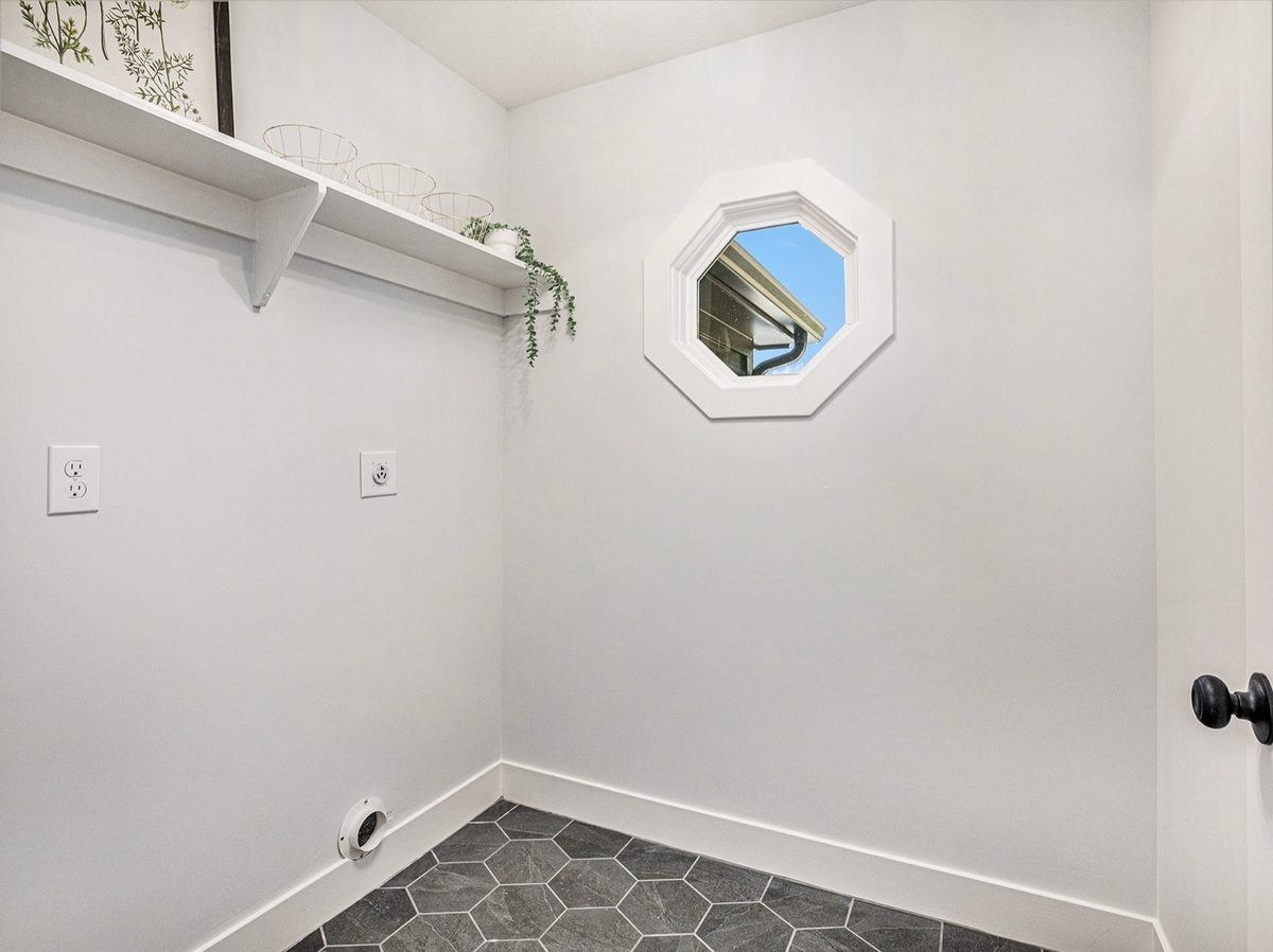 After: bright white laundry room with hex-tile floors and the same octagon window