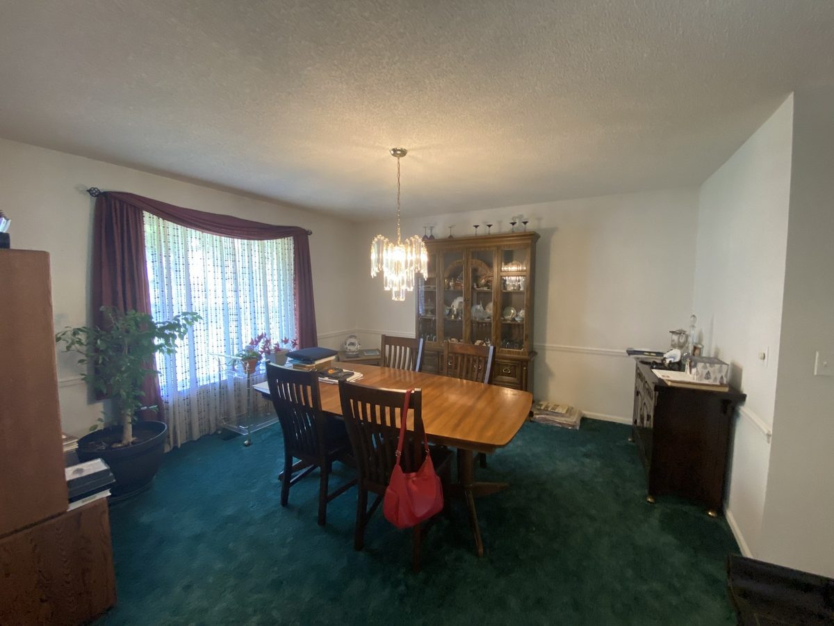 Before: formal dining room with teal-green carpet, burgundy drapes, and a wood china hutch