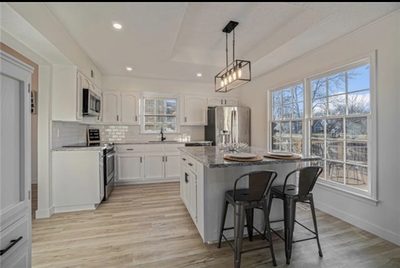 After: bright kitchen with white cabinets, a quartz island, and stainless appliances