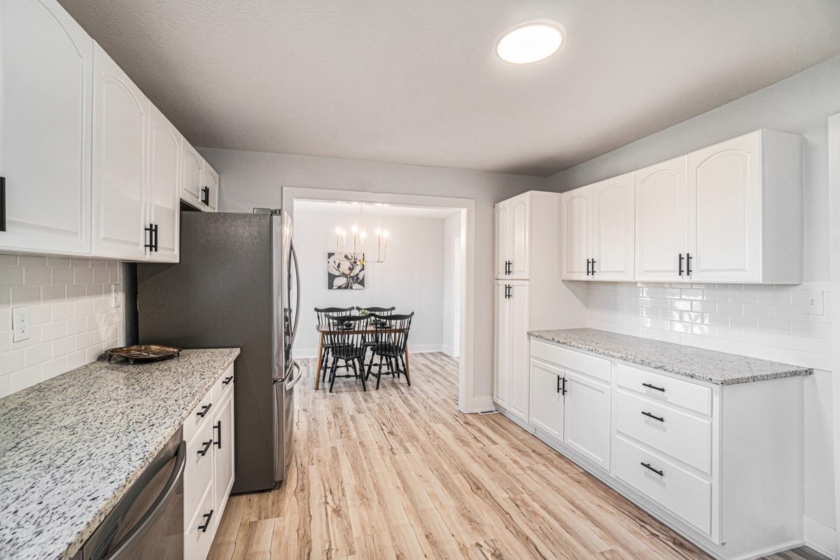 After: refreshed kitchen with white cabinets, granite counters, and stainless appliances