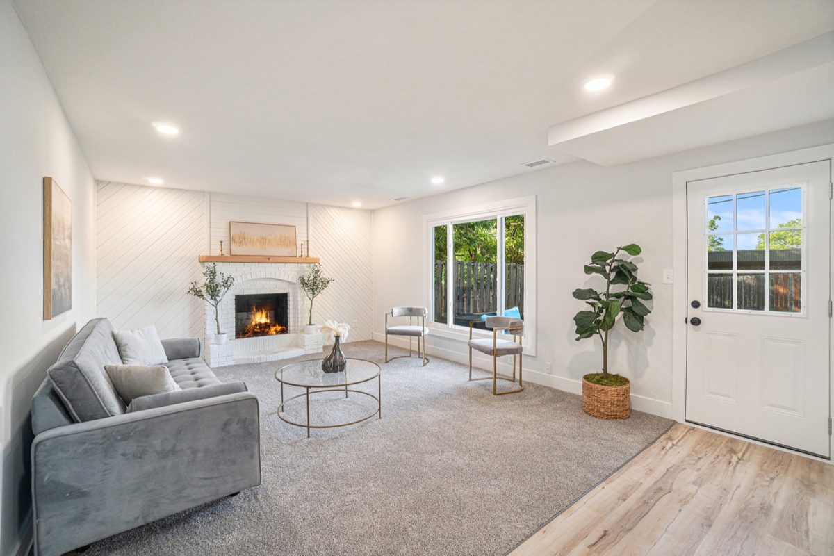 After: bright staged living room with a white-painted brick fireplace and shiplap wall