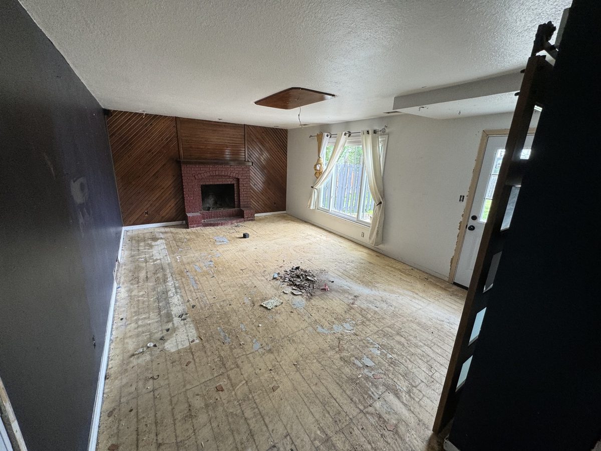 Before: living room with dark wood paneling, a dated fireplace, and bare subfloor